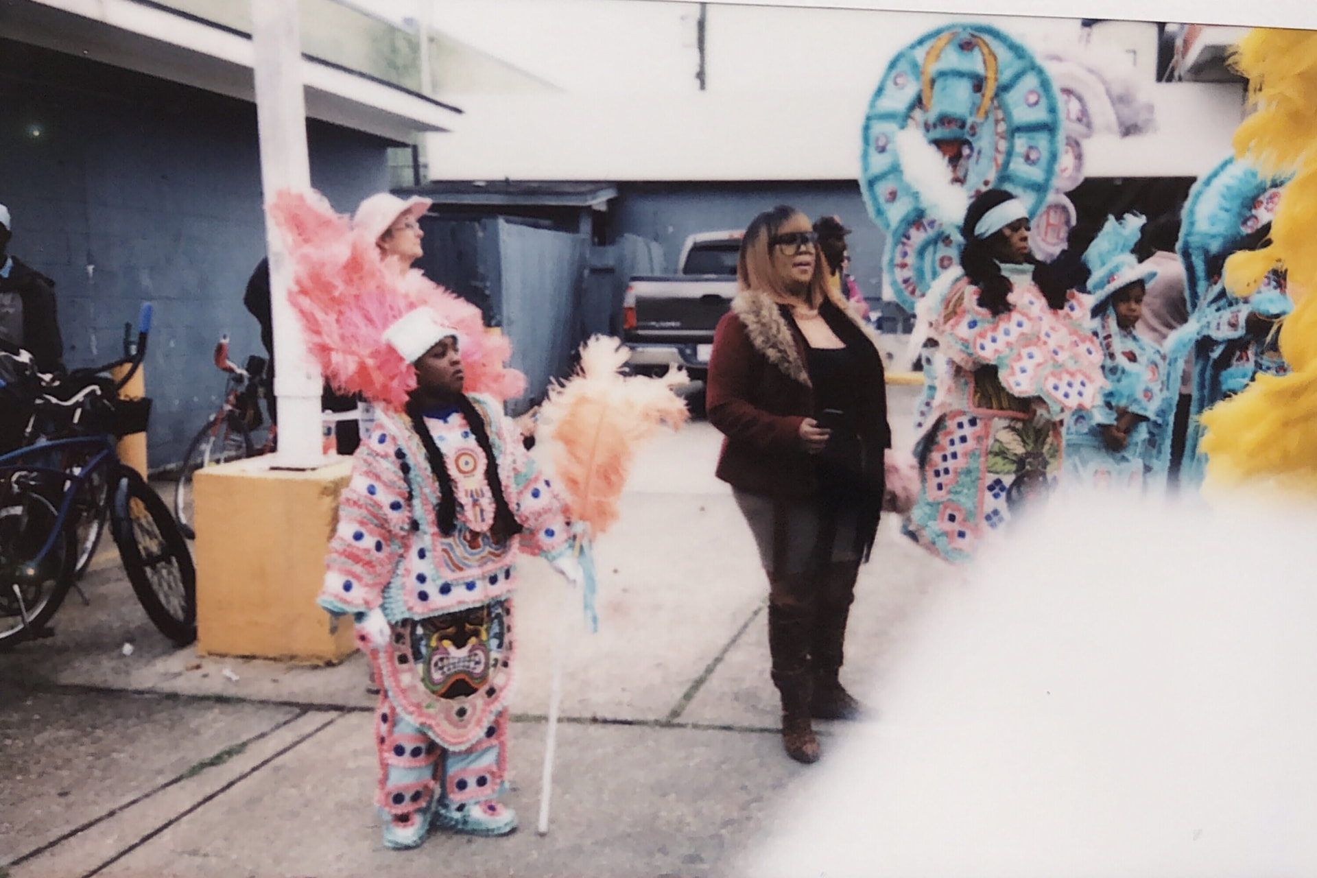 Instant film photo of a woman standing with the Mardi Gras Indians in full regalia