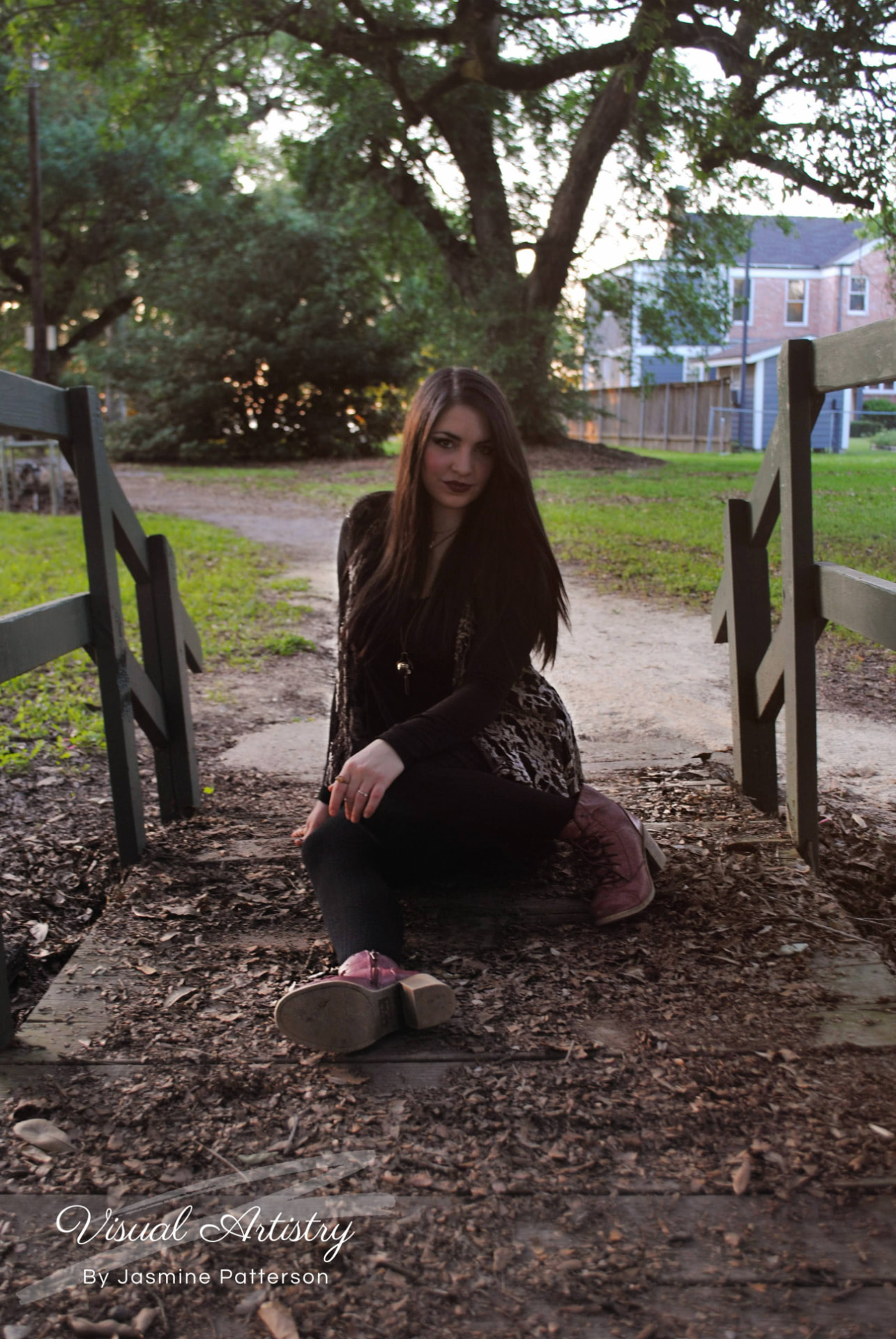 Woman seated on a wooded path between wooden rails