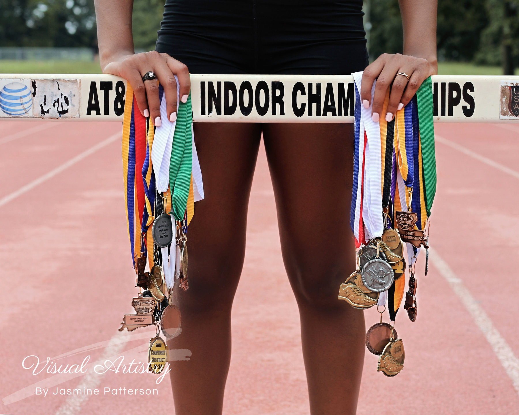 Athlete holding many track medals on an indoor track