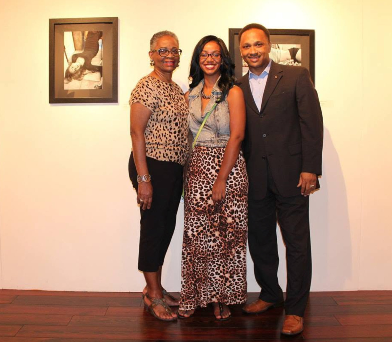 Jasmine Patterson with Ms. Stella and a guest in front of framed photographs at the gallery