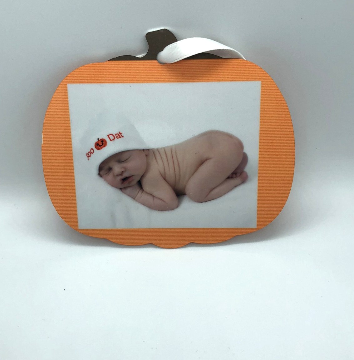 Pumpkin-shaped photo ornament with a sleeping newborn in a pumpkin hat