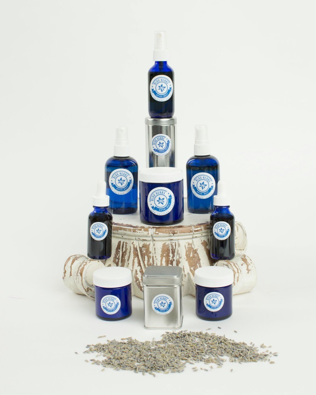 Bluu Herbs products stacked in a pyramid with loose herbs and silver tins in front