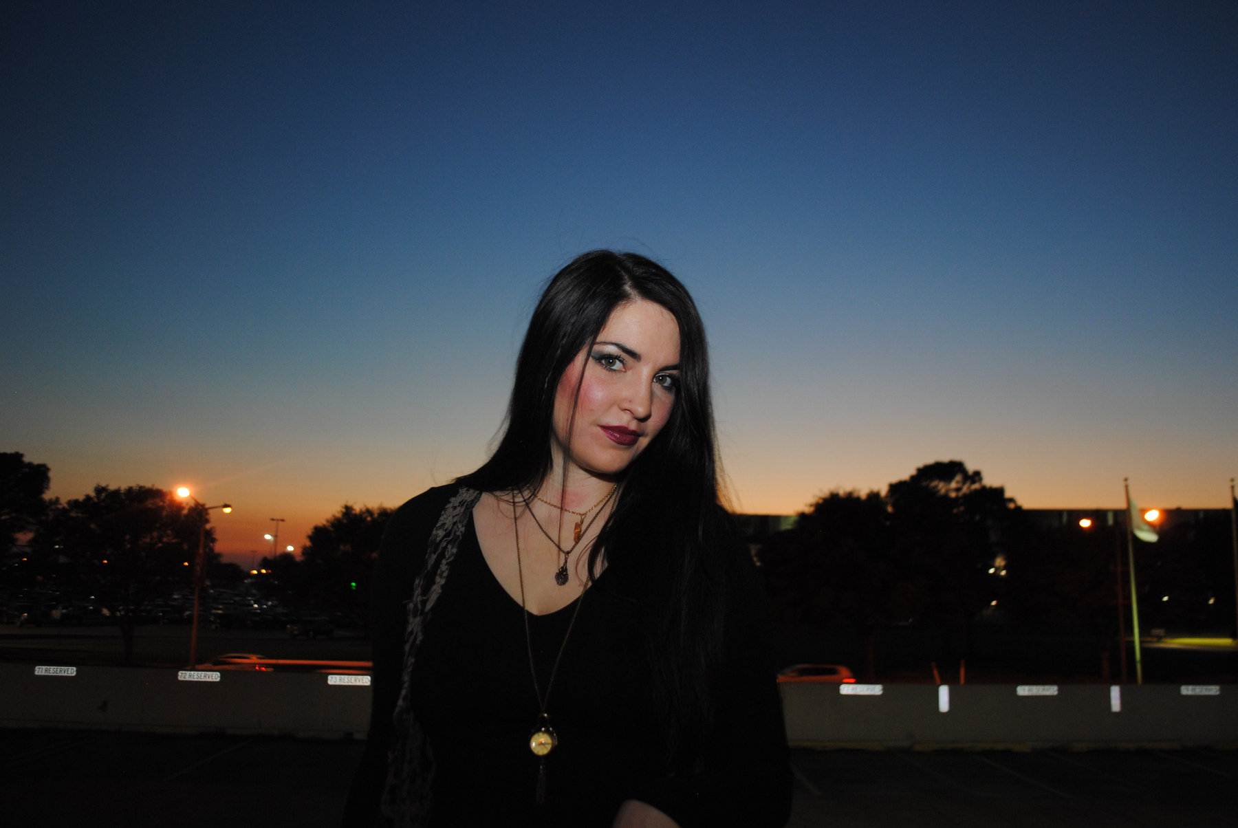 Woman in black photographed at sunset against a glowing sky