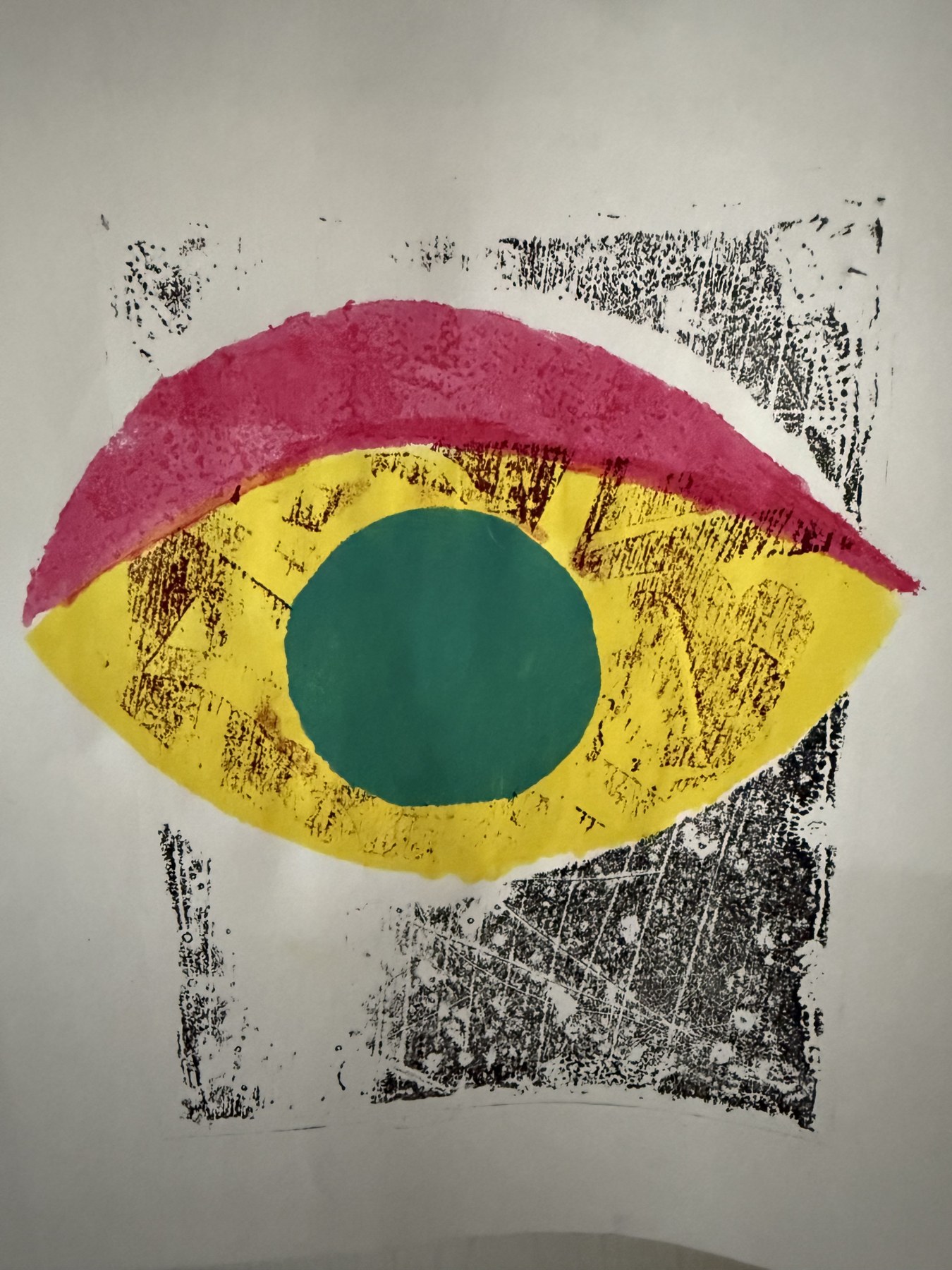 Colorful eye monoprint in magenta, yellow, and green on black-printed paper