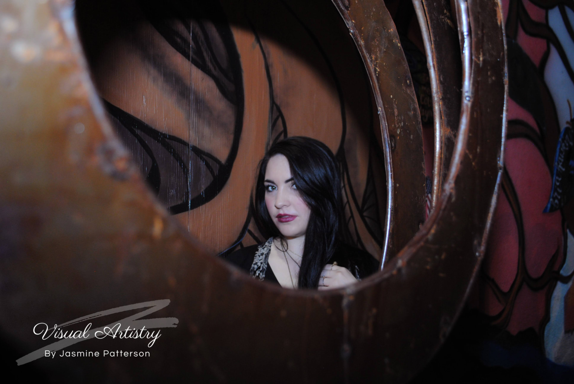 Woman in black and lace seen through a rusted metal sculpture