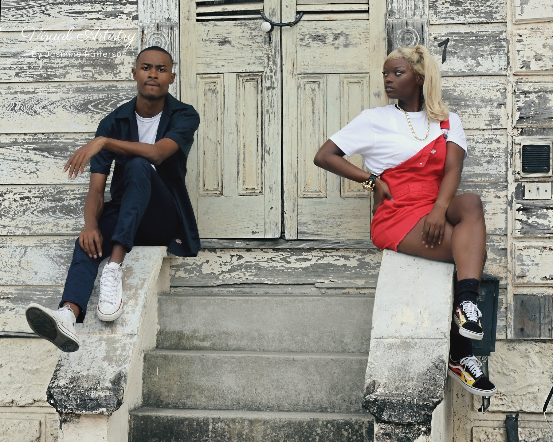 Two models seated on weathered steps in front of old wooden doors