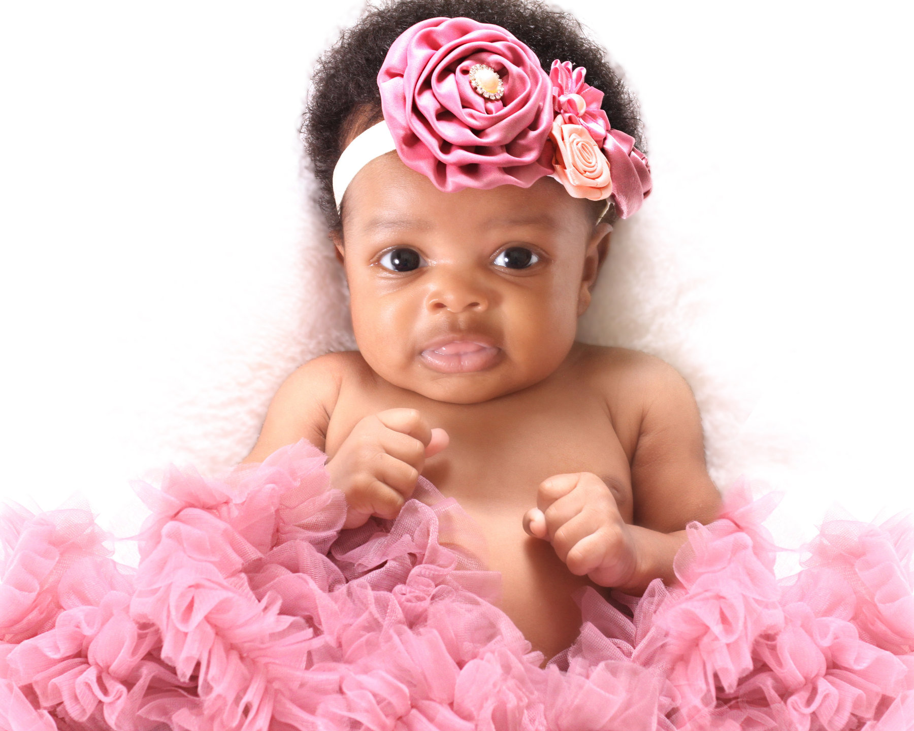Smiling baby girl in a pink tutu and large pink flower headband