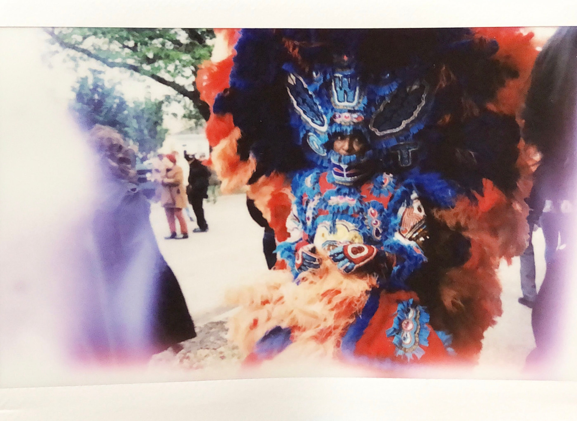 Instant film photo of Mardi Gras Indians in red and patterned suits on a New Orleans street