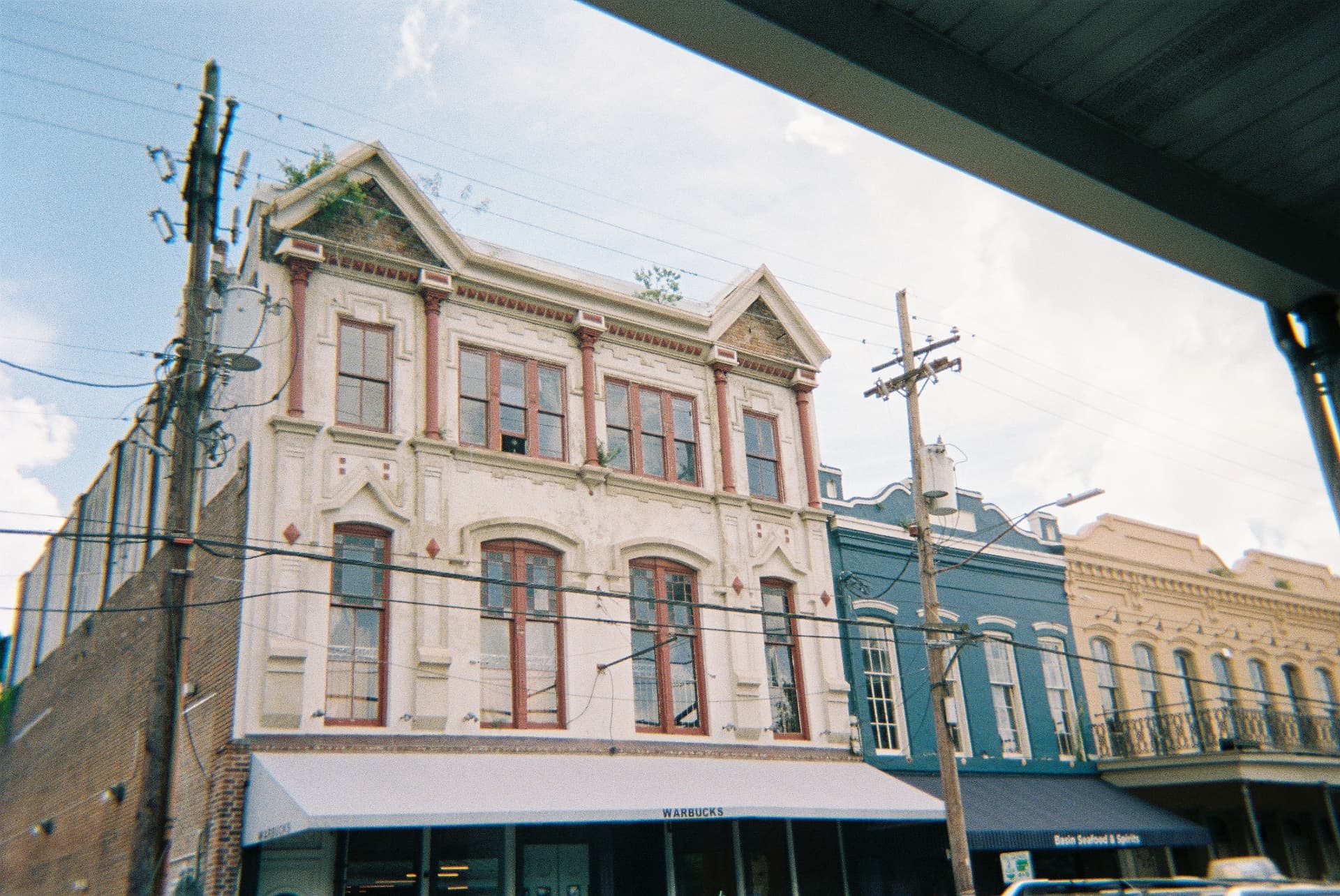 Historic corner storefront with a white awning photographed beneath an overpass