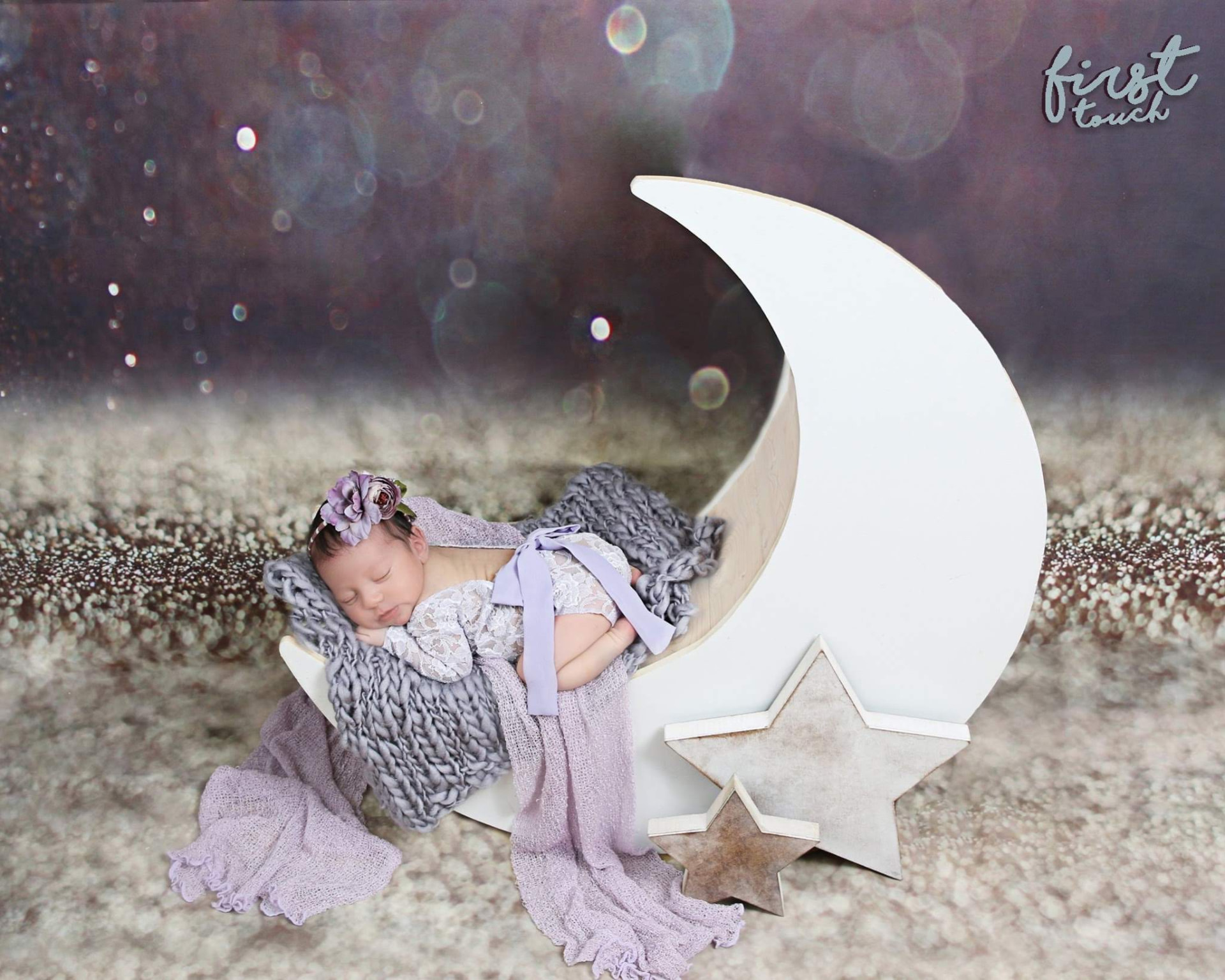 Newborn baby in a lavender outfit sleeping on a crescent-moon prop against a purple backdrop