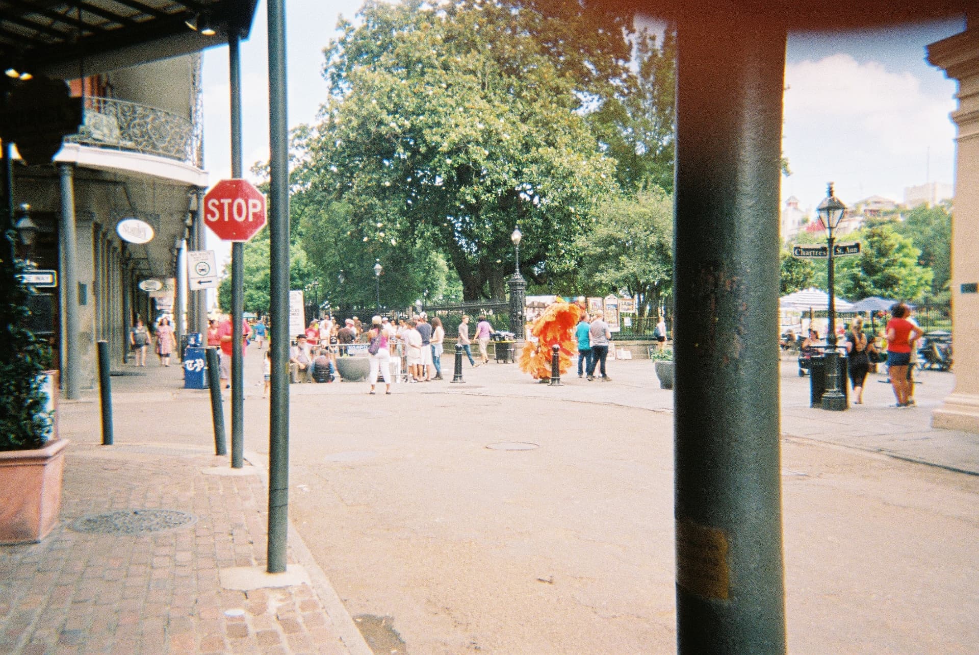 Jackson Square crowd and a costumed performer seen past a stop sign, New Orleans