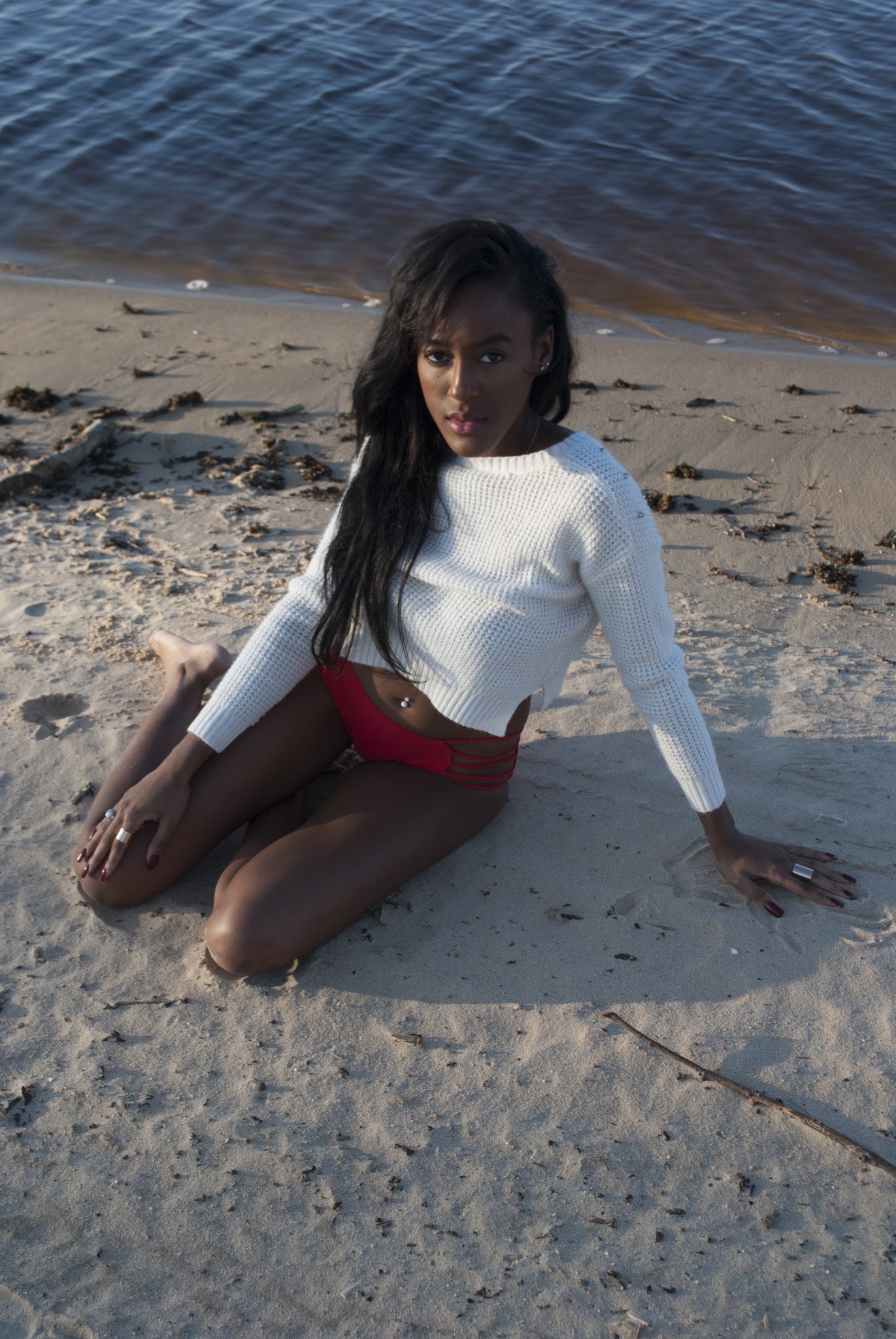 Woman seated on the sand by the water at golden hour