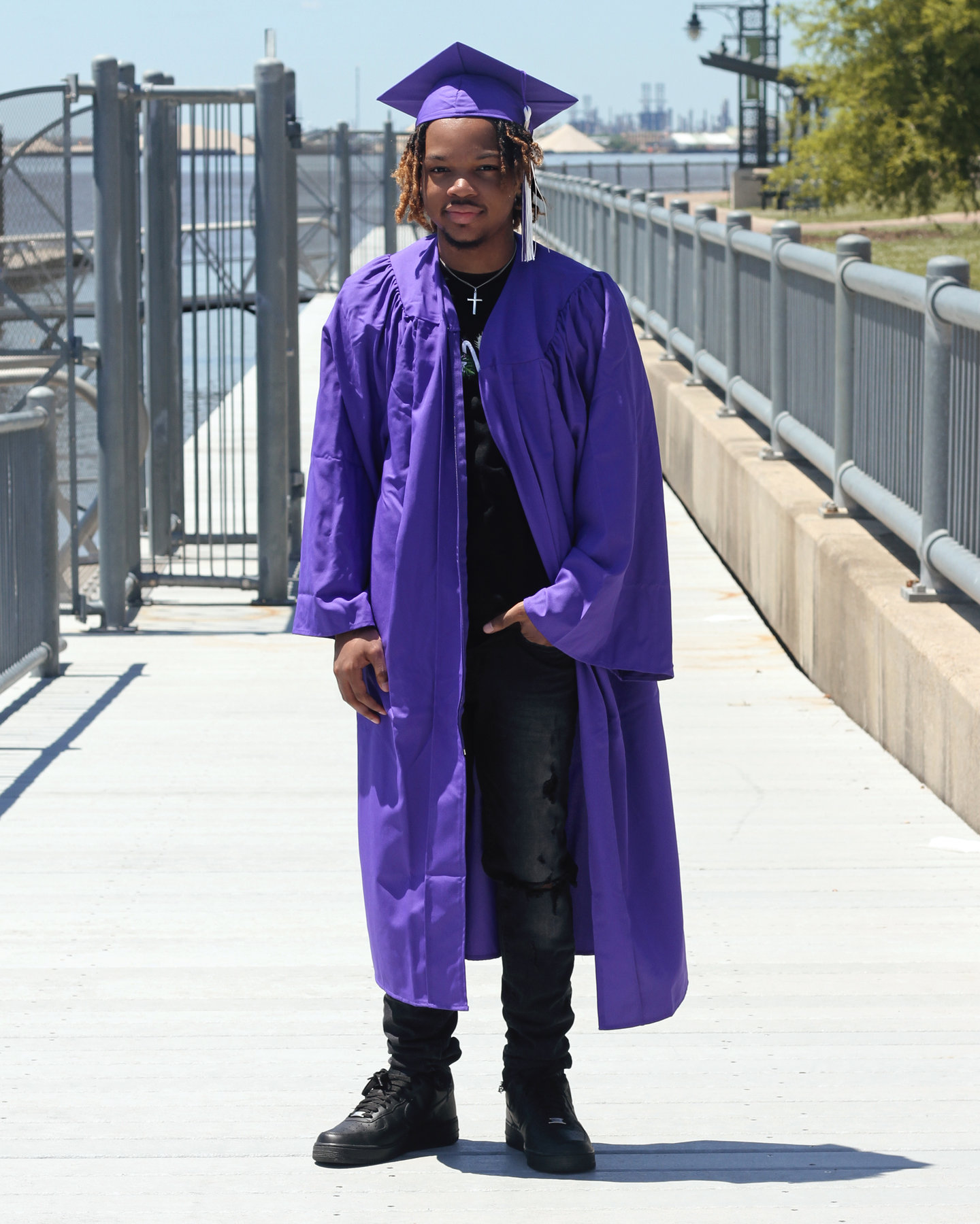 Graduate in a purple cap and gown on a boardwalk