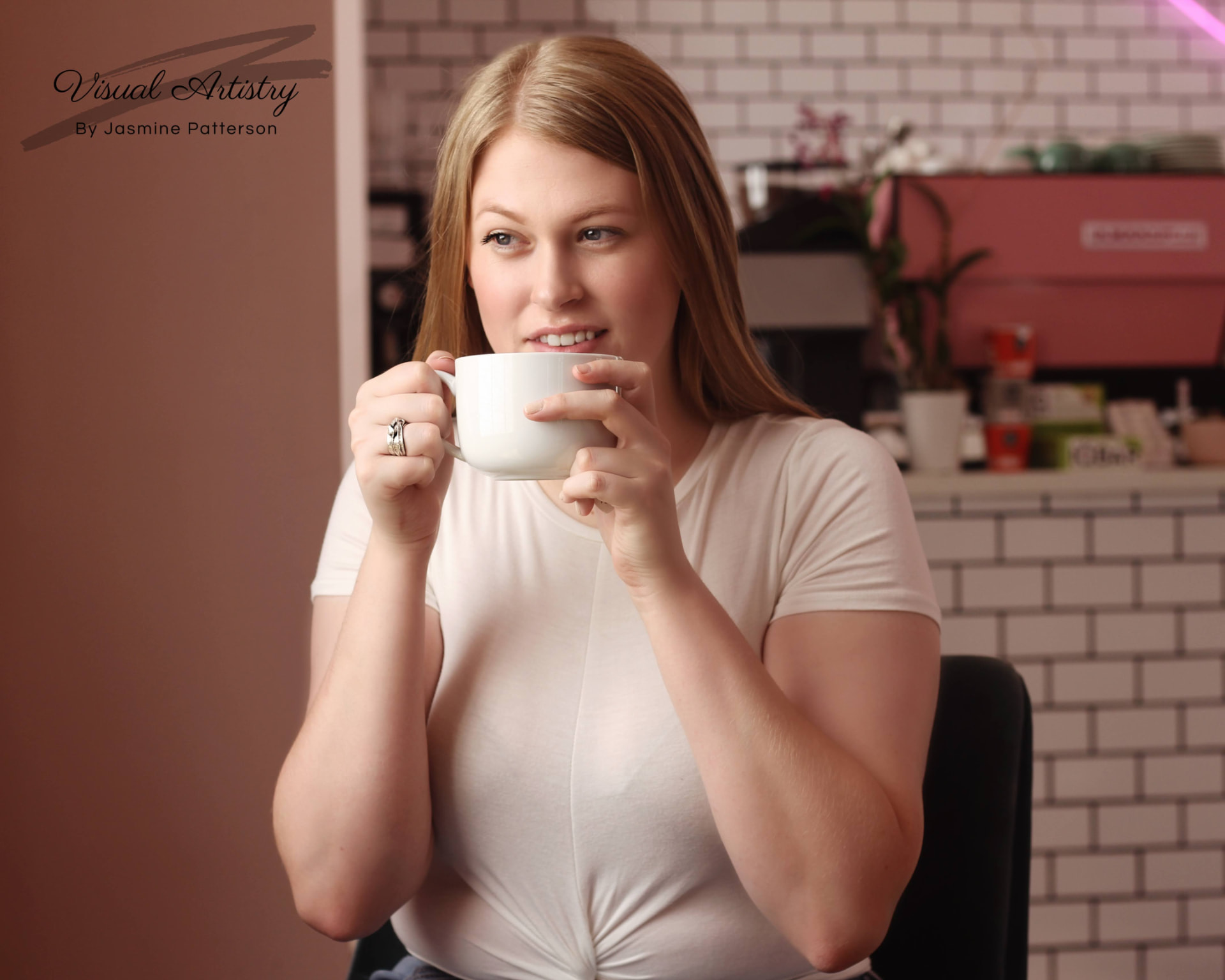Woman smiling over a white coffee cup in a café