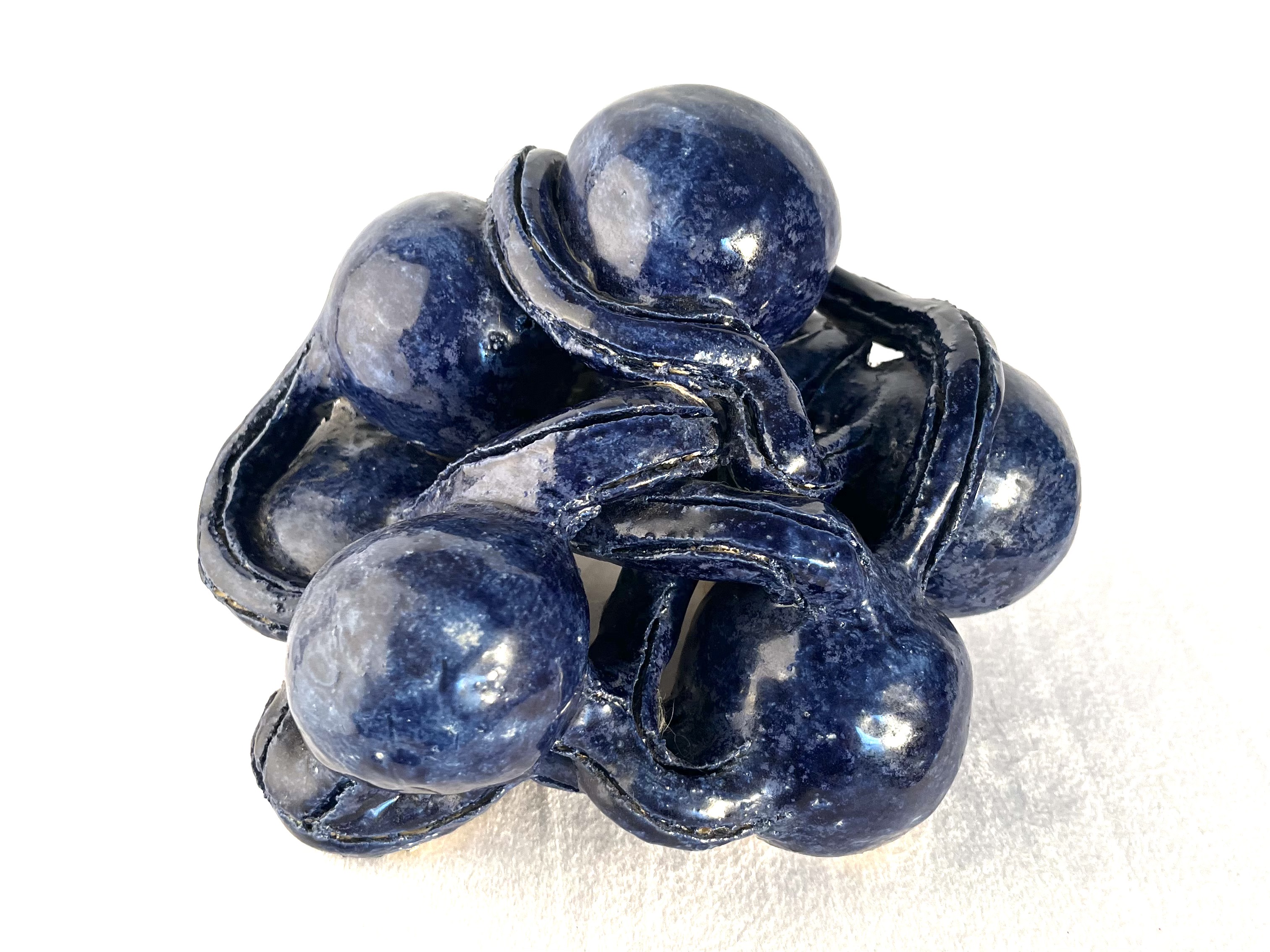 Glossy deep-blue ceramic sculpture built from clustered rounded forms
