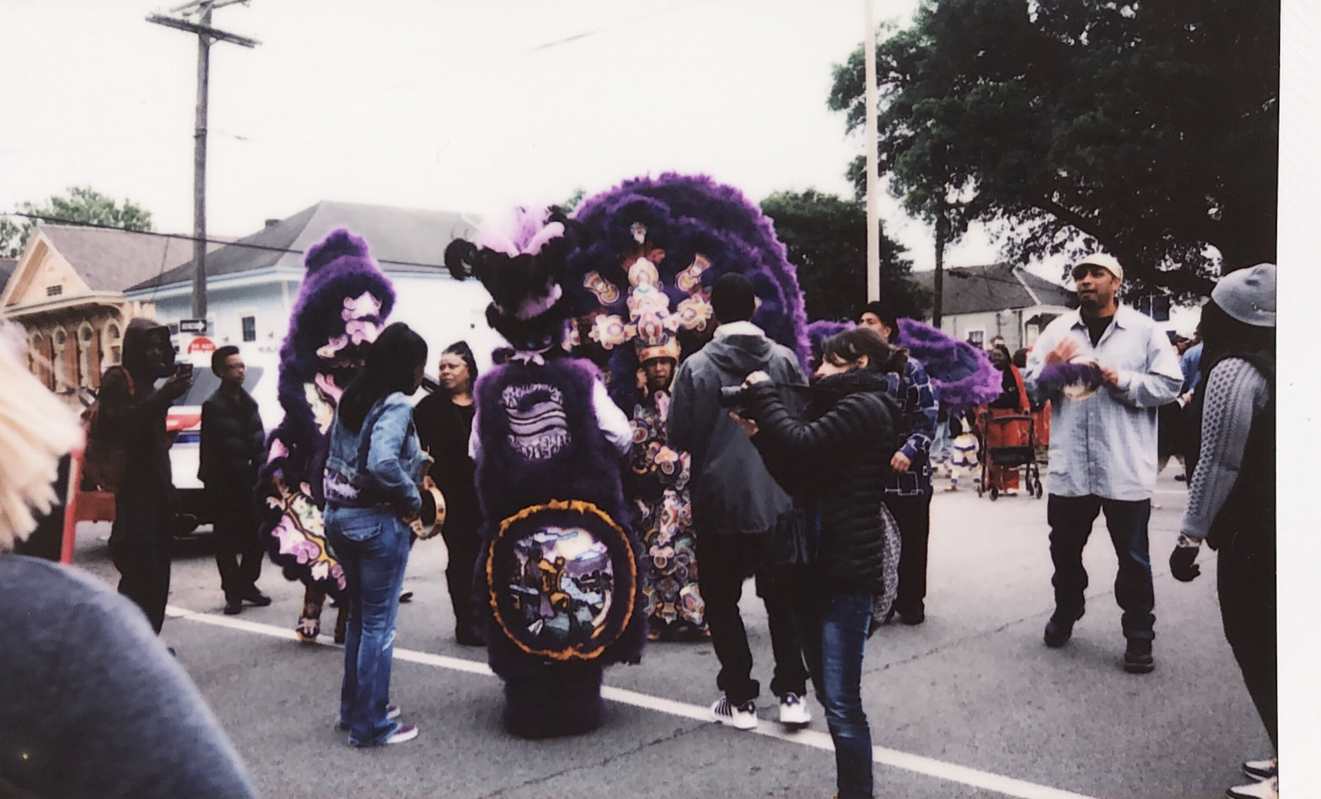 Instant film photo of Mardi Gras Indians in purple suits at a street gathering