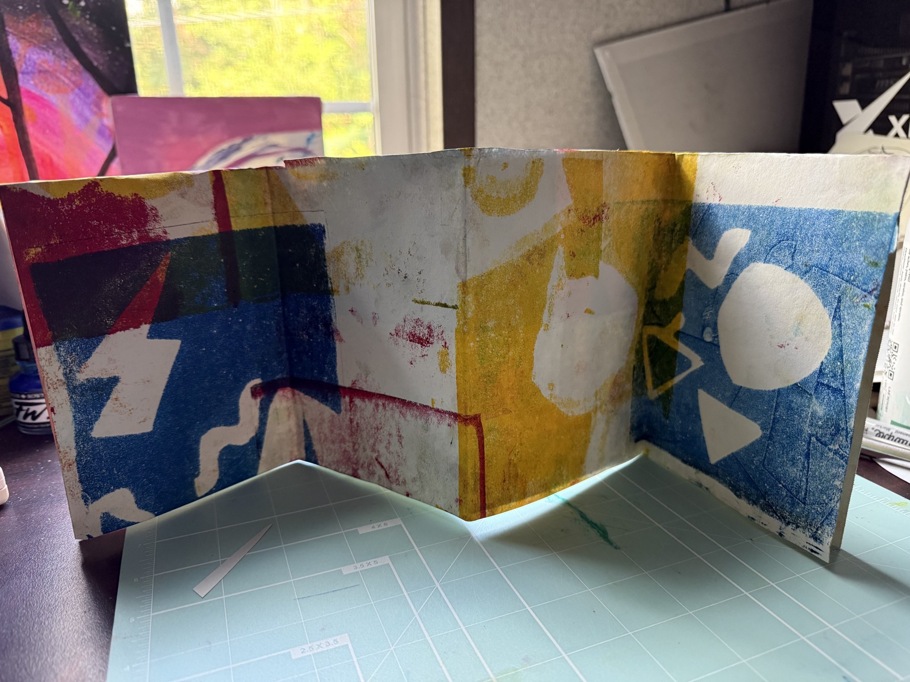 Accordion artist book unfolded showing a series of printed panels