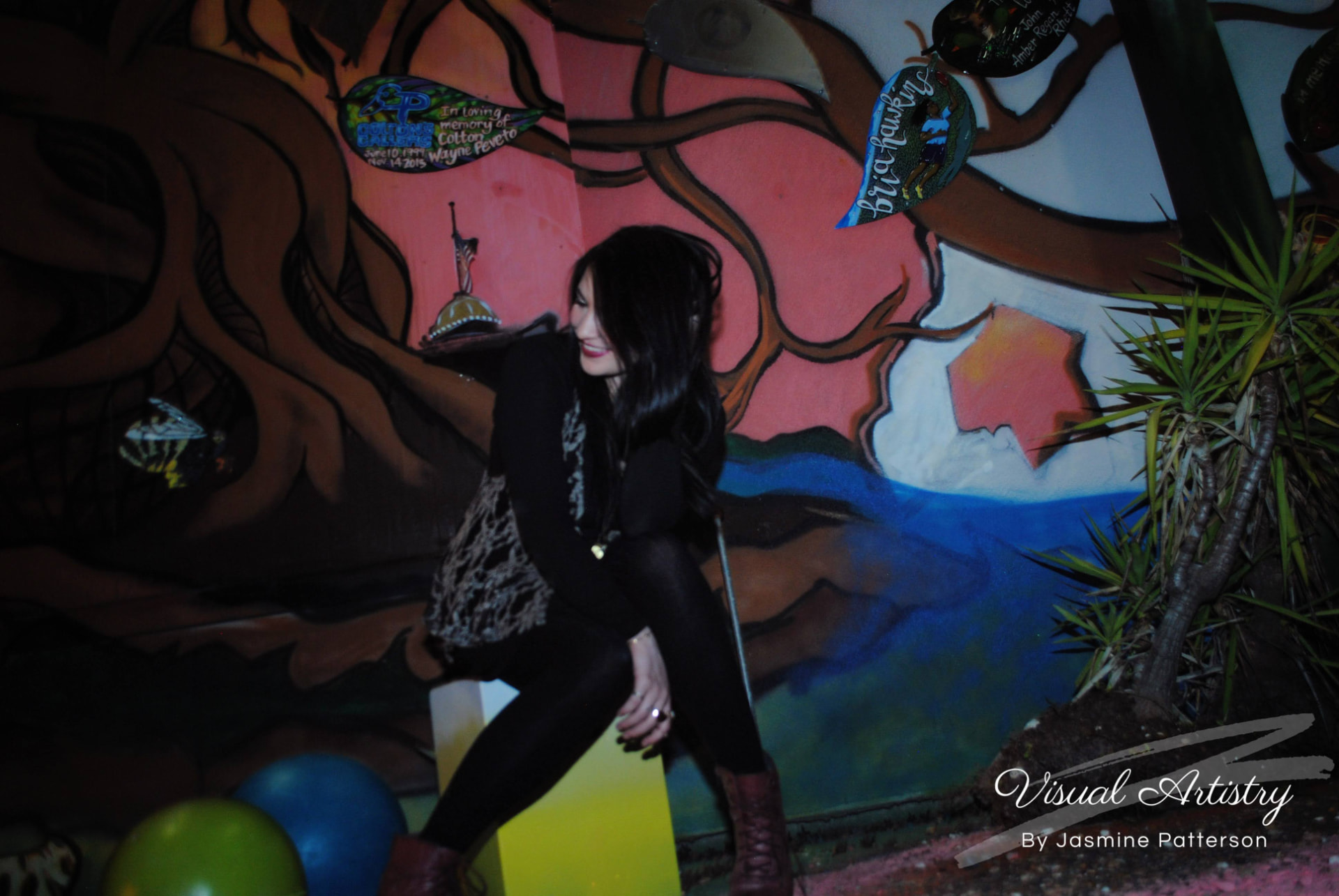 Woman in black and lace laughing in front of a painted mural at night