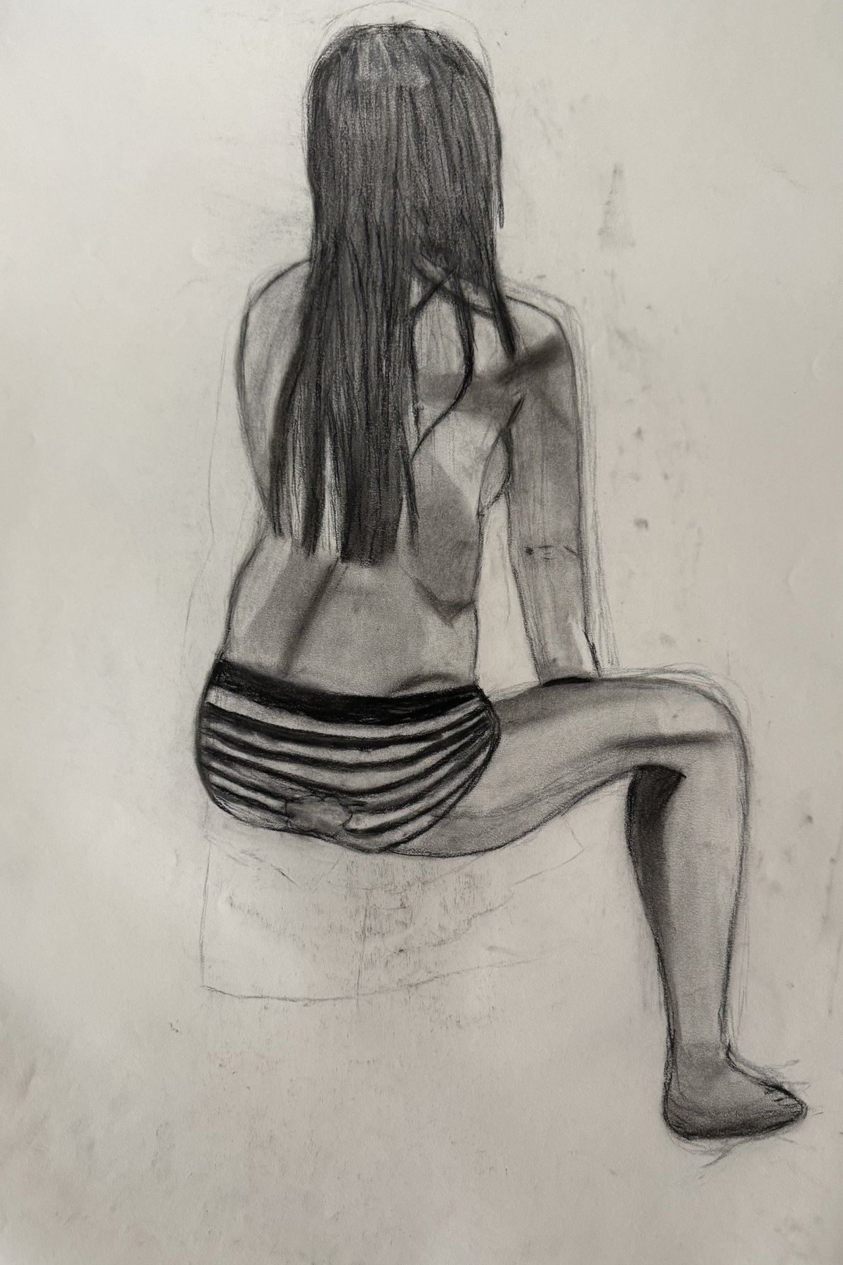 Charcoal drawing of a seated figure seen from behind