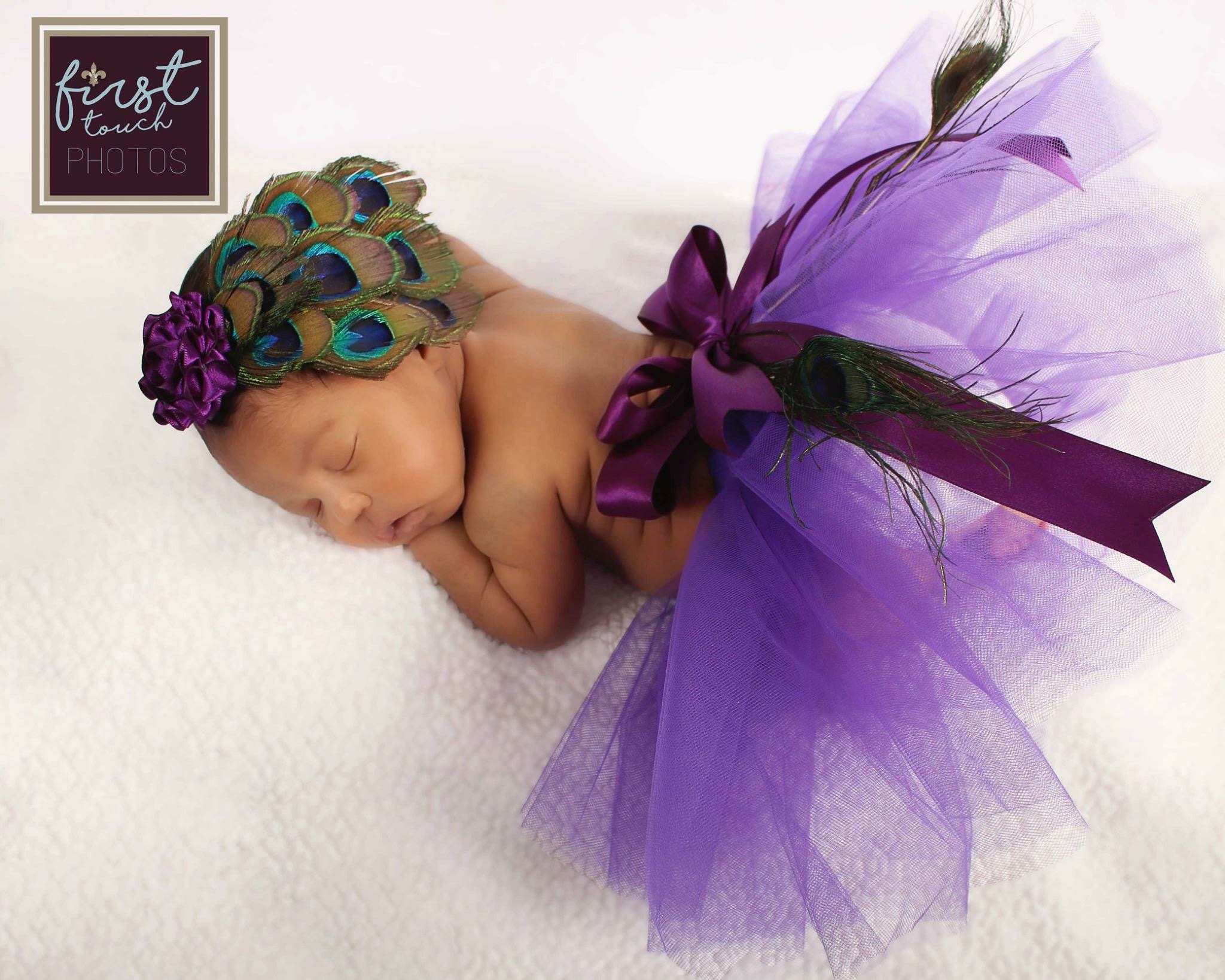 Sleeping newborn in a purple tutu and peacock headpiece