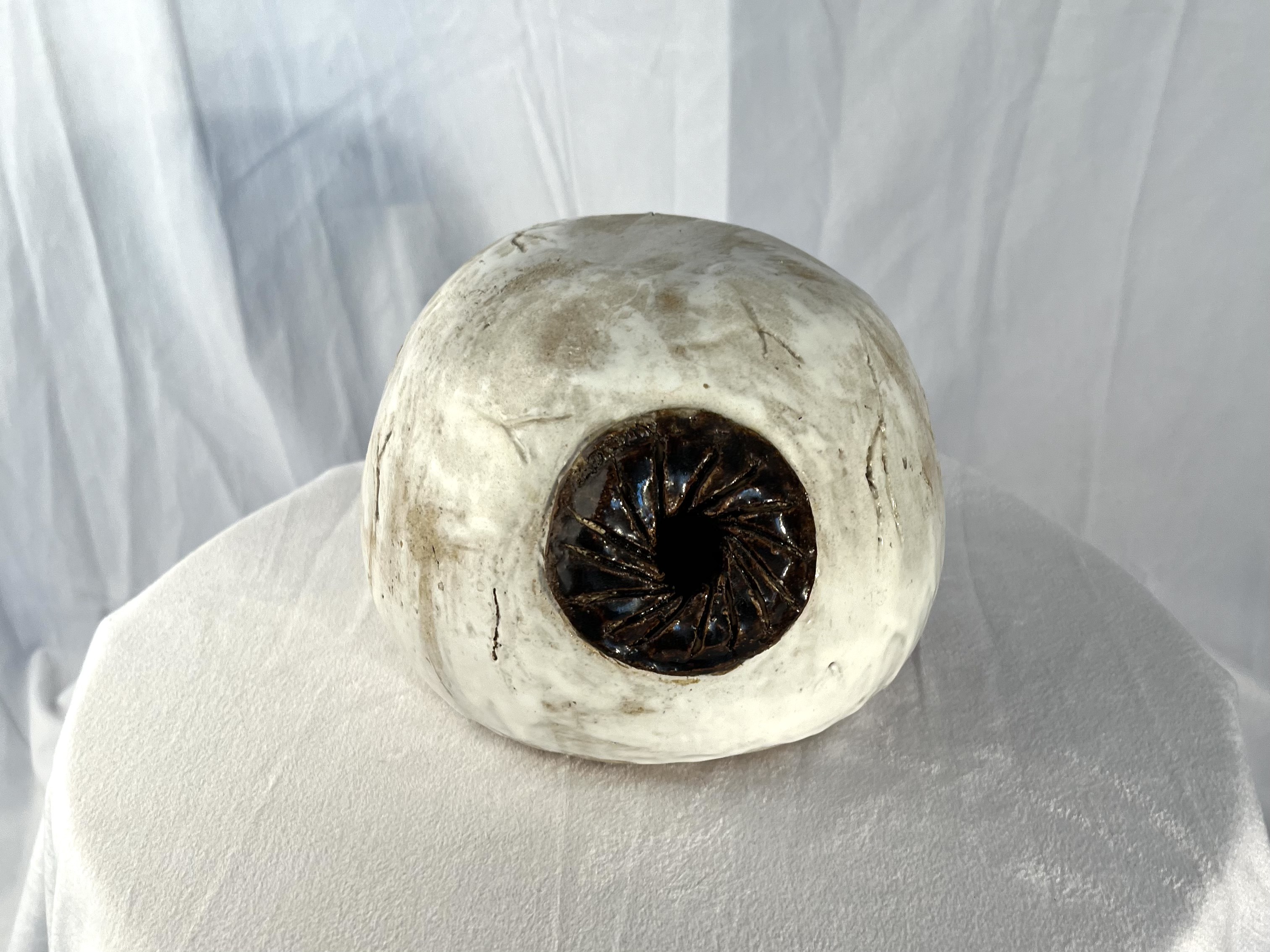White ceramic sphere with a dark circular opening resembling an eye