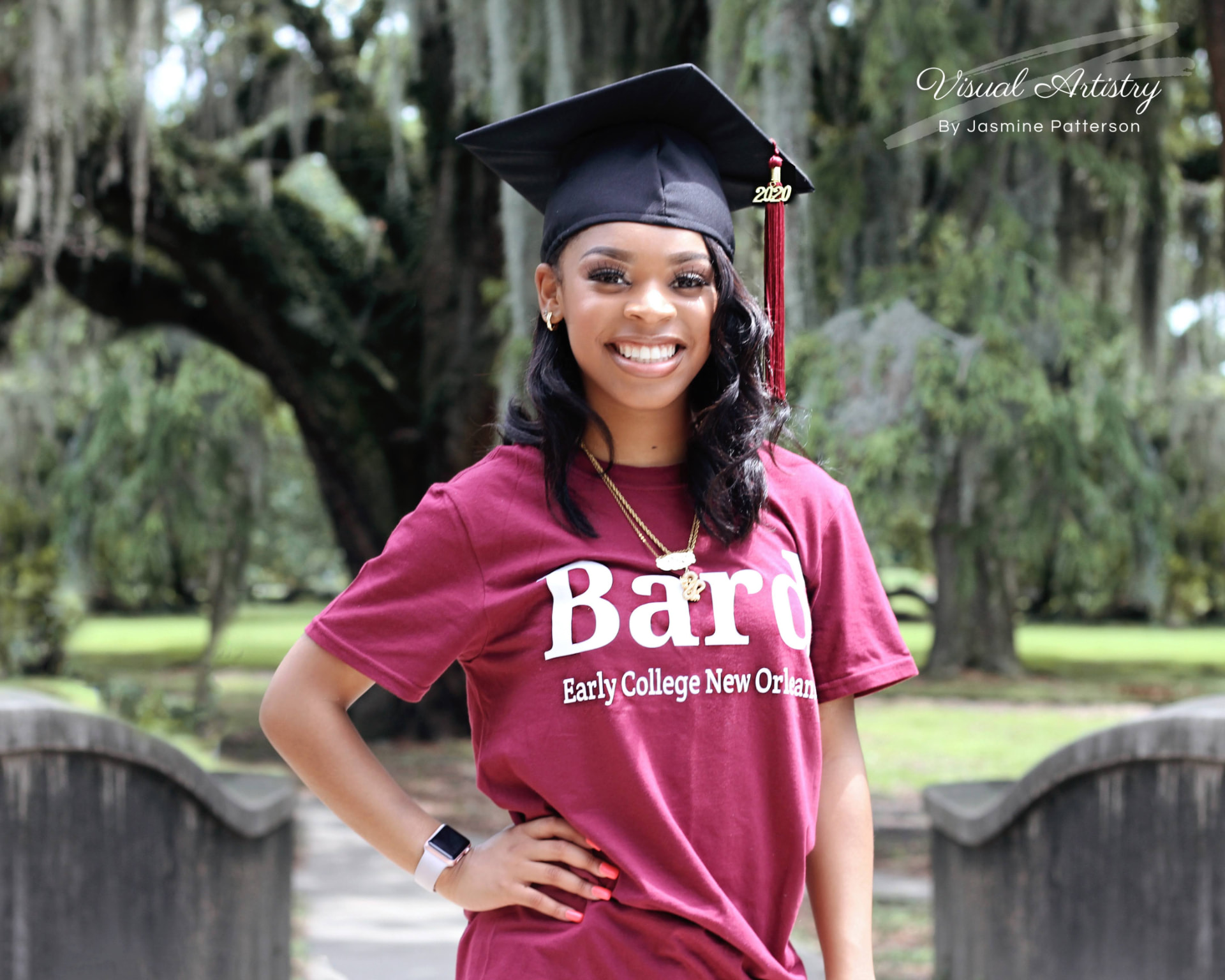 Graduate in a black cap with a 2020 tassel and a Bard Early College New Orleans shirt on a wooden bridge