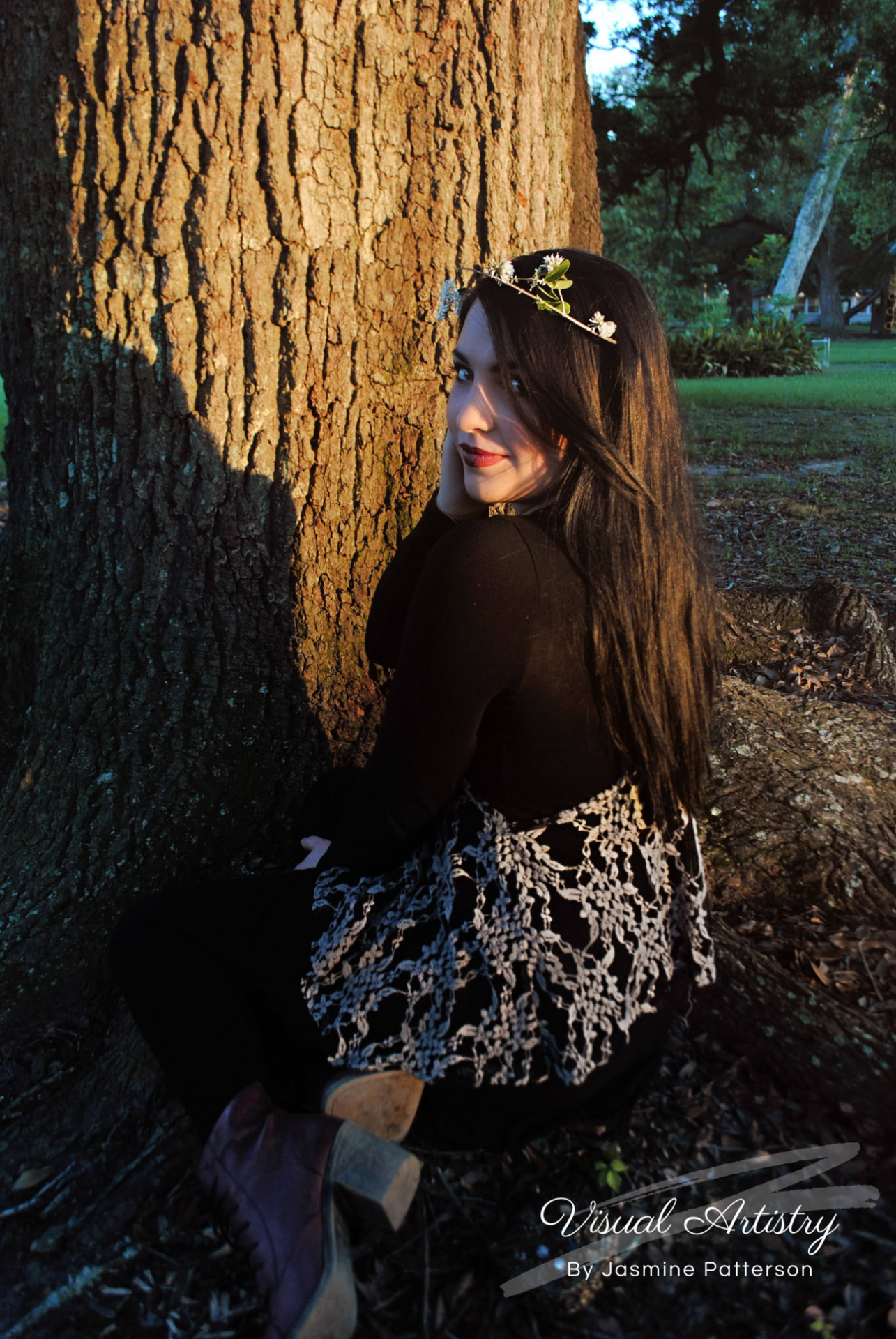 Woman in black and lace seated at the base of an oak tree